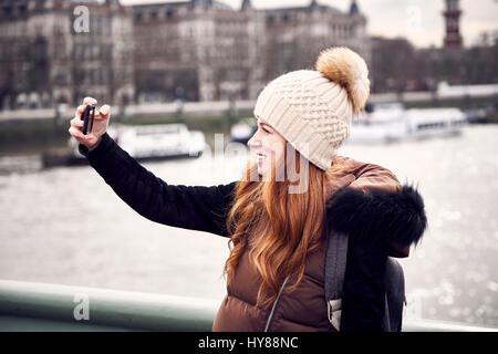 A young woman takes a selfie on Parliament Bridge in London Stock Photo