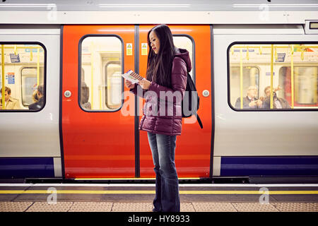 A young Japanese woman at a tube station in London Stock Photo