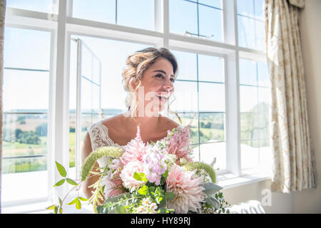 A bride in her bridal suite holding a bouquet of flowers prior to her wedding Stock Photo