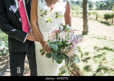 A bride and groom on their wedding day with a bouquet of flowers Stock Photo