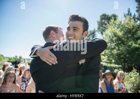 A groom and best man share a hug prior to the wedding service Stock Photo