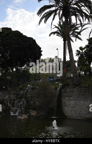 Small artificial waterfall in a park between the rocks Stock Photo