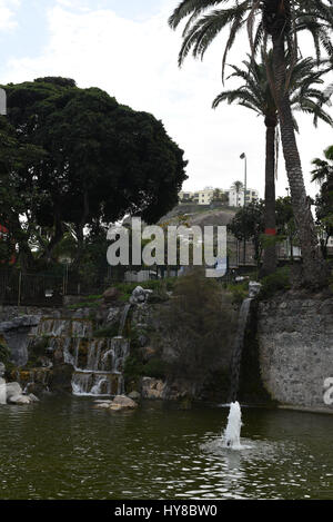 Small artificial waterfall in a park between the rocks Stock Photo