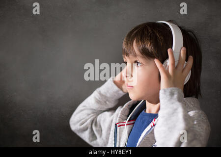 Cute boy with phone and head phones, listening music, indoors, studio shot Stock Photo