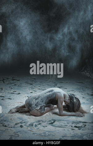 Woman lies on the floor, sprinkled with flour, in a dark room. Stock Photo