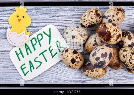 Quail eggs and Easter card. Felt chicken on wooden background. Stock Photo