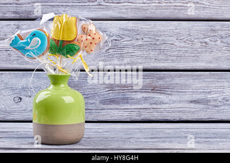 Vase with biscuits, wooden background. Easter cookies wrapped in plastic. Stock Photo