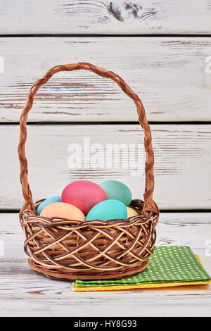 Easter basket and napkins. Pile of colorful chicken eggs. Stock Photo