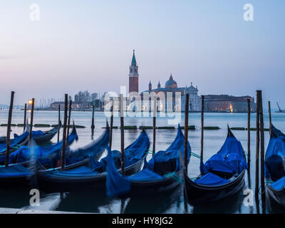 Pre-dawn view of Gongolas moored at St Mark's Square (Piazzo San Marco) with Cheese di San Giorio Maggiore in background, Venice, Italy Stock Photo