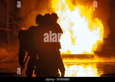 Group of firefighters in front of burning tank during firefighting exercise