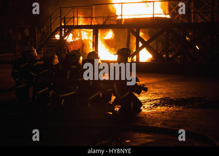 Group of firefighters kneeling in preparation to fight fire in firefighting exercise Stock Photo