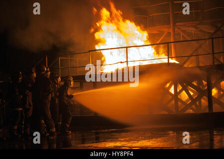 Firefighters hosing down burning structure during firefighting exercise Stock Photo