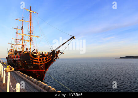 Old wooden ship at pier. Old ship on blue sky background. Perfect travel background. Copy space on blue sky background. Stock Photo