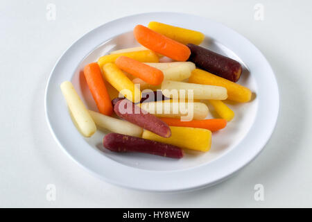 Closeup on plate of baby rainbow carrots on white plate on white background- healthy eating concept Stock Photo
