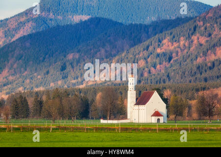 Beautiful white church on the green meadow on the background of trees and mountains in Germany. Spring landscape in Europe. Chapel and green hills wit Stock Photo