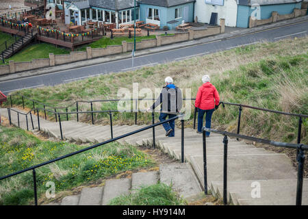 A mature man and woman walking down the steps to the beach area at Saltburn,England,UK Stock Photo