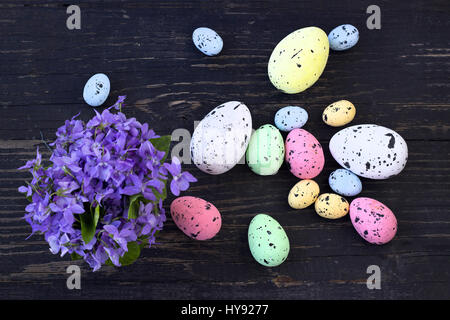 Easter eggs and violets on dark wooden planks Stock Photo