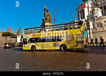 Sightseeing Christian Rome Bus passing through Monument to king Victor Emmanuel II, and monument of the Unknown Soldier at Venice Square. Rome, Italy Stock Photo