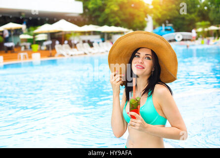 Real female beauty enjoying her summer vacation at swimming pool with alcohol cocktail Stock Photo