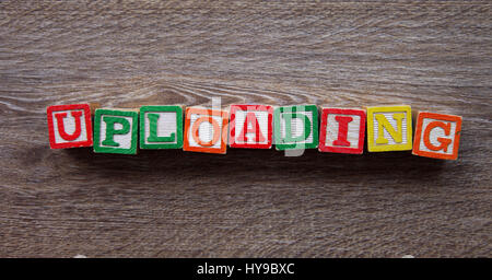 Wood Block letters forming the word UPLOADING Stock Photo