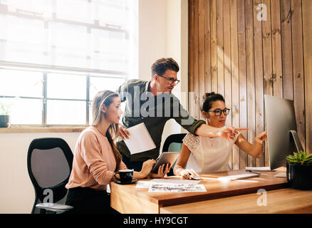 Shot of creative business team looking at a computer and discussing new ideas. Business colleagues working together on computer in office. Stock Photo