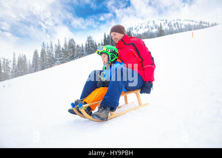 Father and his little son enjoying a sledge ride in famous ski resort in Tyrolian Alps, Zillertal, Austria Stock Photo