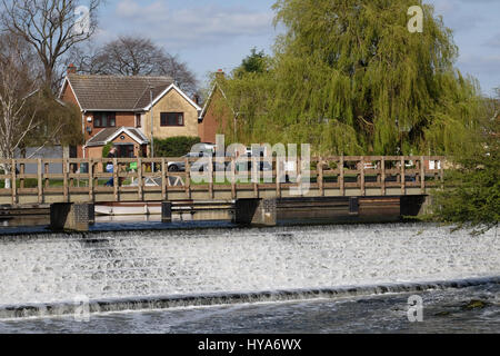 woman walking across barrow weir in the spring sunshine Stock Photo