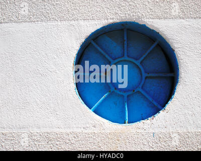 Strange round blue closed window in the plastered wall Stock Photo
