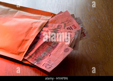 Brown envelope stuffed full of cash. Pay off or bribe with a bundle of cash. Stock Photo