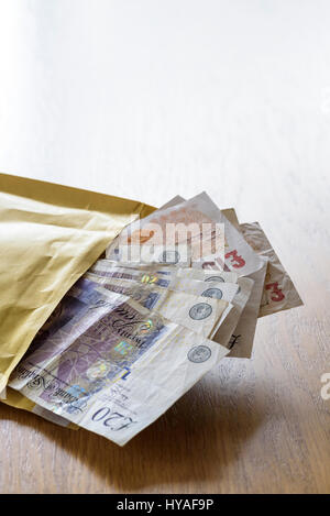 Brown envelope stuffed full of cash. Pay off or bribe with a bundle of cash. Stock Photo