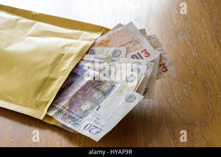 Brown envelope stuffed full of cash. Pay off or bribe with a bundle of cash. Stock Photo