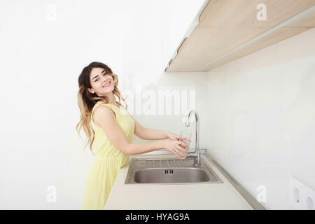 Woman Pouring Glass Of Water From Tap In Kitchen Stock Photo