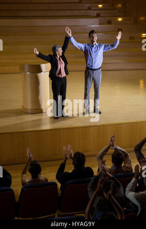 Female business executive appreciating a colleague on stage at conference center Stock Photo