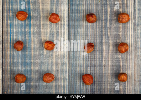Twelve hazelnut nuts without a shell are arranged in three rows on a wooden background Stock Photo