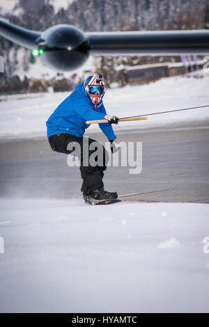 ENGADIN AIRPORT, SWITZERLAND: A BRITISH snowboarder reached speeds of 78 miles-per-hour and became the first person to snowboard while be towed by a commercial AEROPLANE. Daredevil Jamie Barrow (22) of the British Snowboard Cross Team is the UK’s fastest snowboarder and completed the incredible stunt by hanging from the wing of an aircraft Engadin Airport in Switzerland. Pictures show how Jamie skilfully snowboarded on the snowy edge of the runway, despite the frantic speed the aeroplane was travelling. Stock Photo