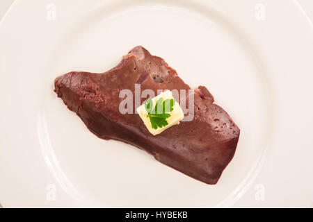 high angle view of  a raw veal liver isolated on white plate with butter and parsley Stock Photo