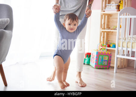 Cute boy taking first steps holding mums hands Stock Photo