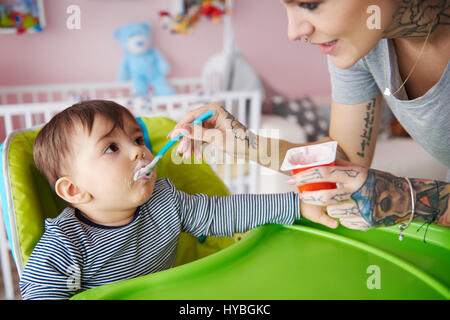 Baby boy eating in his high chair Stock Photo