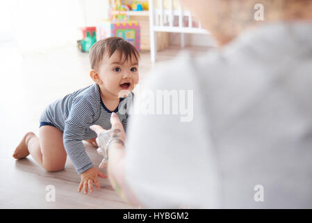 Mother watching baby son crawl towards her Stock Photo