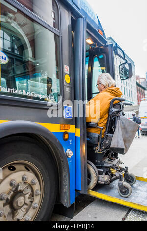 Man in wheelchair boards accessible bus via ramp, Vancouver, British Columbia, Canada. Stock Photo
