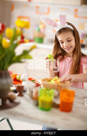 Girl preparing Easter basket with colored eggs Stock Photo