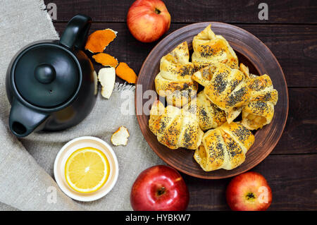 Home made croissants (bagels) with apples, decorated with poppy seeds in a clay bowl on a dark wooden background. Top view. Stock Photo