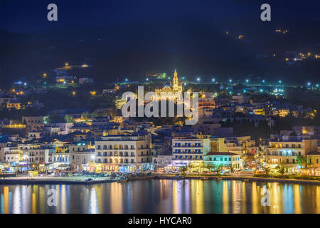 Aerial panoramic view of Tinos town. Centered the famous church of Virgin Mary illuminated at night. Tinos island Cyclades, Greece. Stock Photo