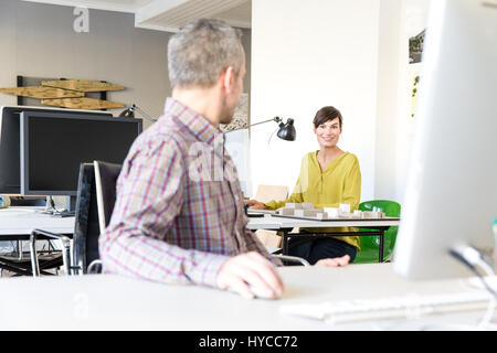Architects in office using computer, talking and smiling Stock Photo