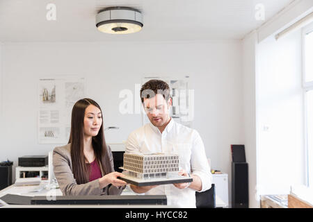 Architects in office holding architectural model Stock Photo