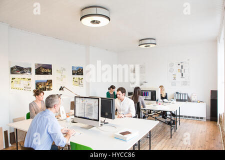 Colleagues in office sitting at desks using computers Stock Photo