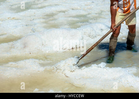 Worker shoveled the salt crystallizes out of the ground in salt farm , filled with natural salt from the sea. Trapani, ITALY Stock Photo