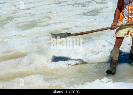 Worker shoveled the salt crystallizes out of the ground in salt farm , filled with natural salt from the sea. Trapani, ITALY Stock Photo