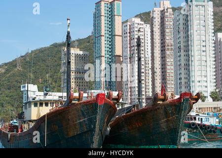 Commercial Fishing Boats Moored In Aberdeen Channel, High Rise Apartment Buildings On Hong Kong Island Behind. Stock Photo