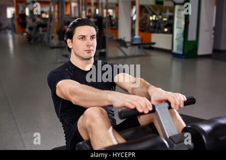 Fitness athlete doing exercises on vertical bench press machine with hands and legs Stock Photo